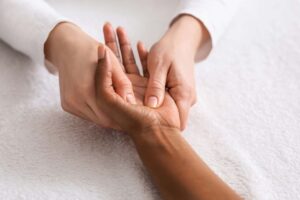 A physiotherapist is performing hand therapy via massage on a clients upturned hand.