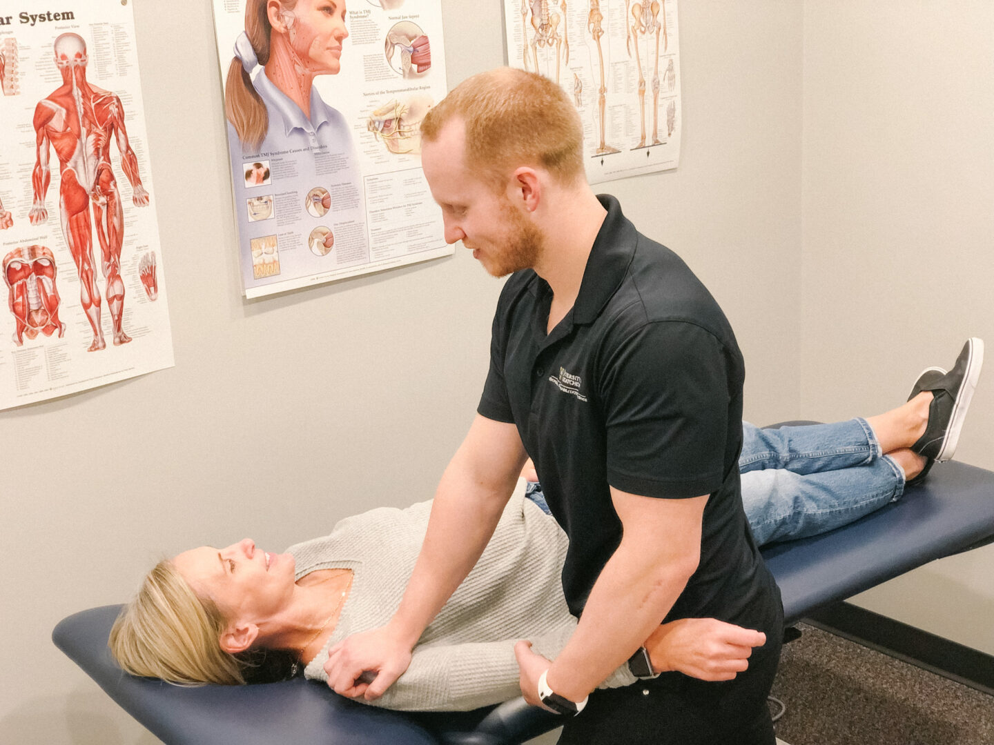 Graeme working on shoulder no mask A Physiotherapist performing manual therapy on a client's shoulder as they lay on a client massage table.