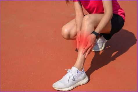 Runner with Shin pain Woman holding lower leg due to shin splints, shin area is highlighted red.